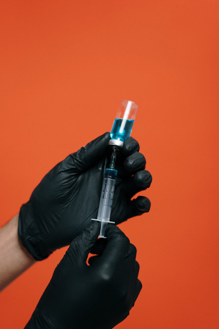 person holding a vaccine with black glovesvaccine
