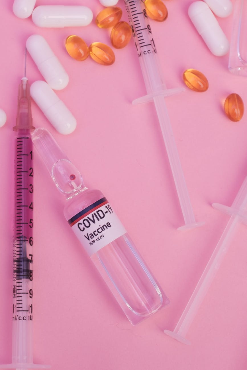composition of coronavirus vaccine on table near syringe and pills