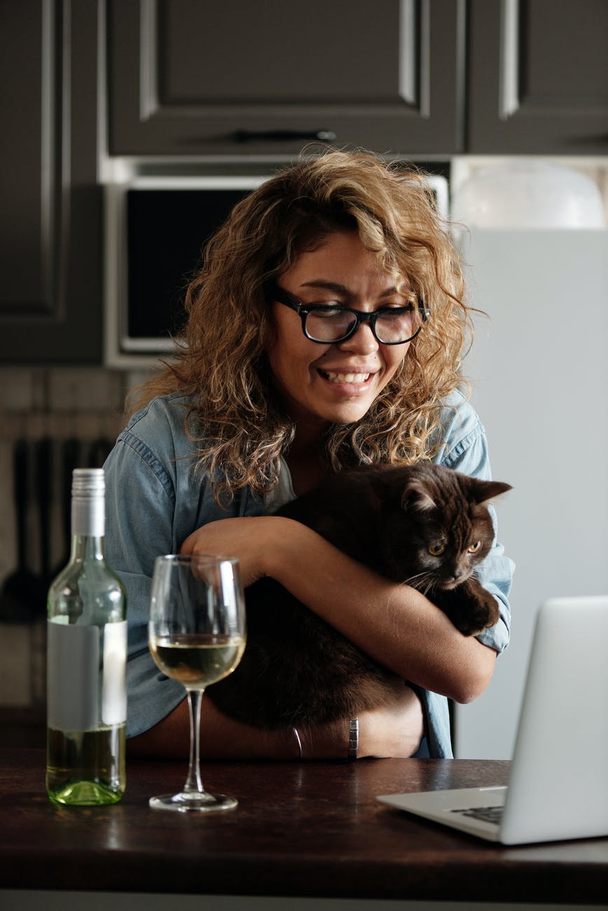 woman in blue denim button up shirt holding black cat