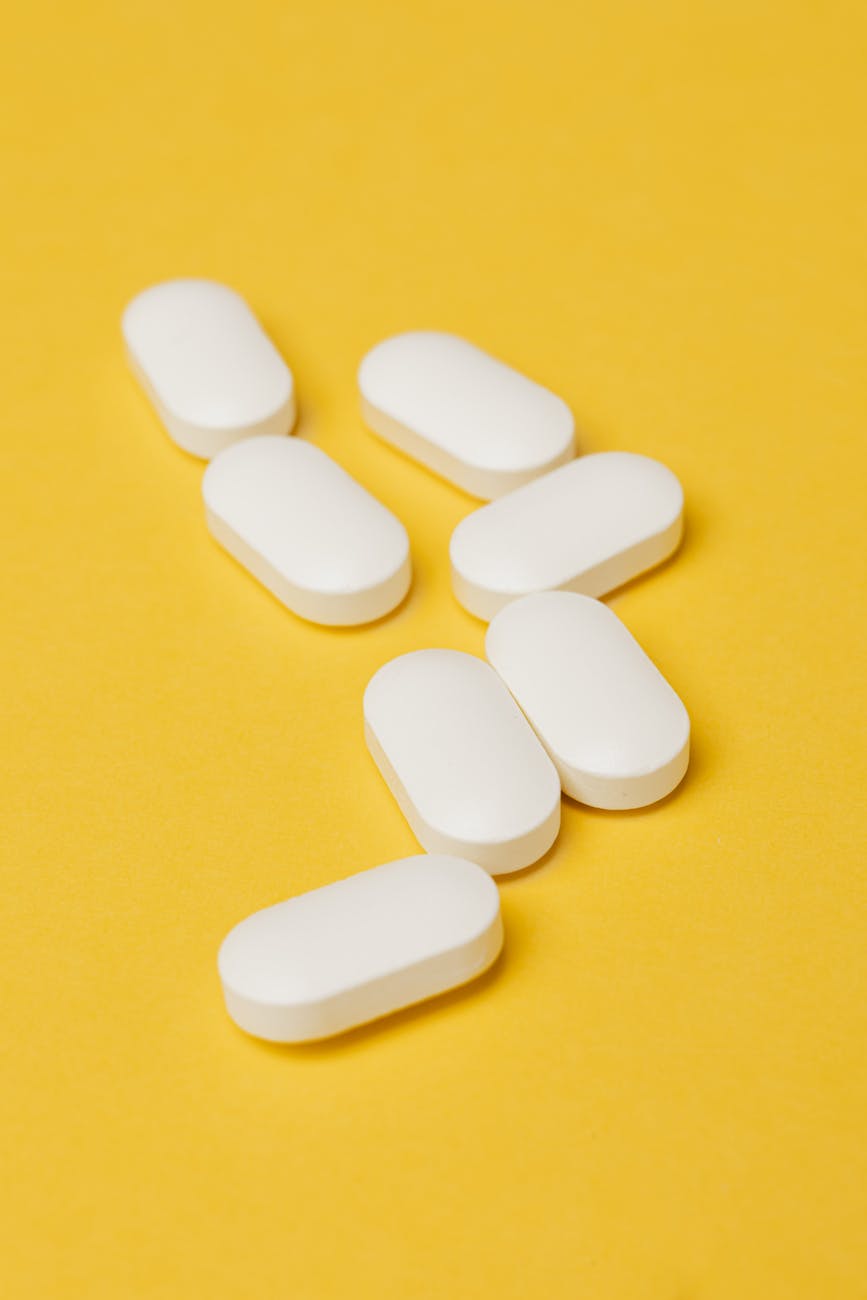 heap of white pills on yellow surface