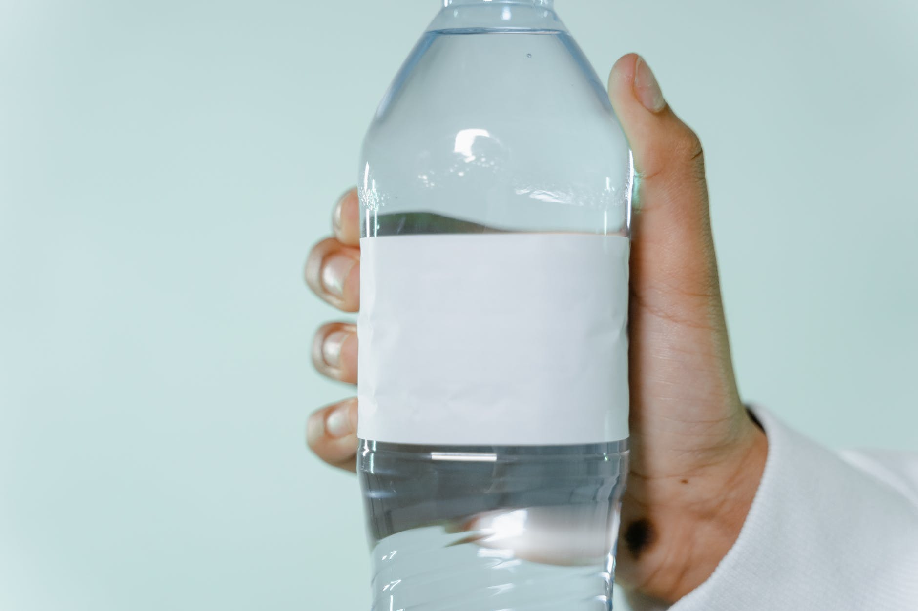 a person holding a water bottle with a blank label