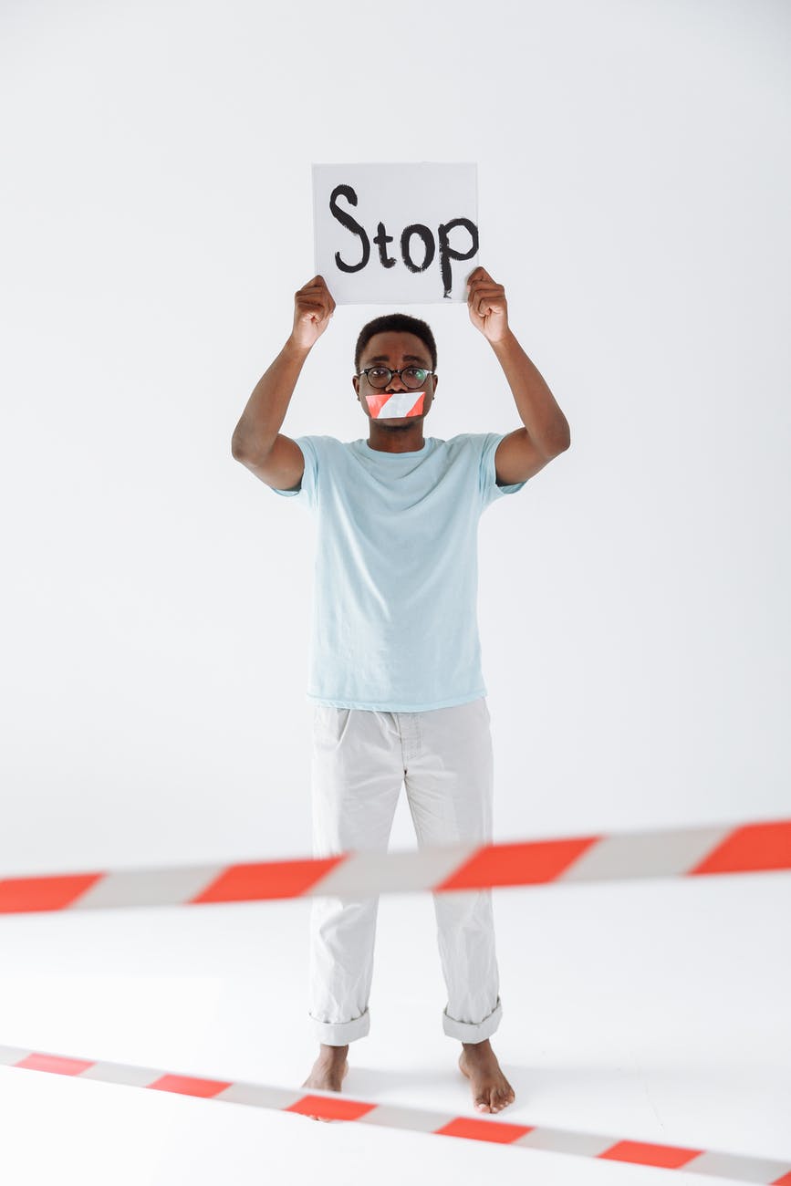 man with mouth tape holding a stop signage