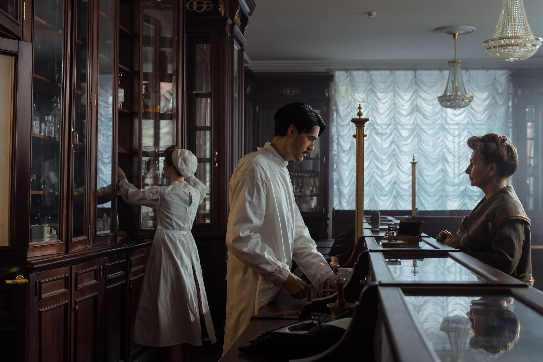 man in white laboratory coat standing in front of an elderly woman
